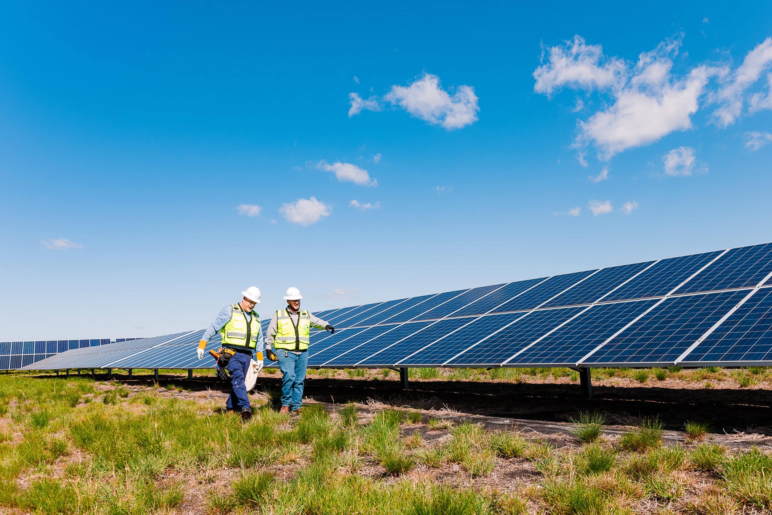 Two solar technicians walking next to a solar panel.