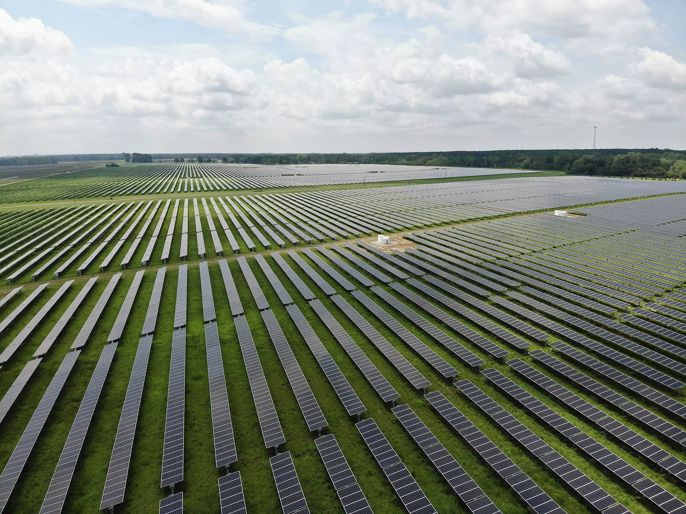 An aerial view of rows of solar panels on a green field