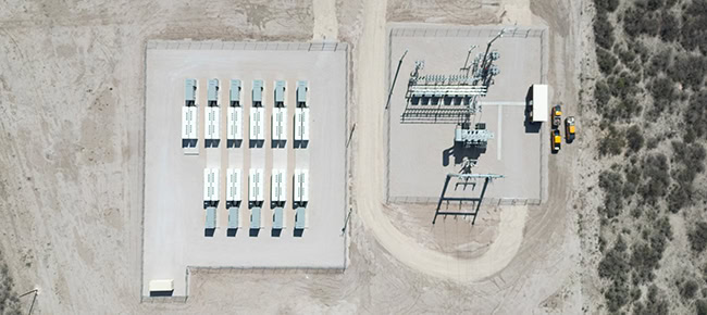 Energy storage containers and a substation are seen from above in a desert and shrub grass landscape